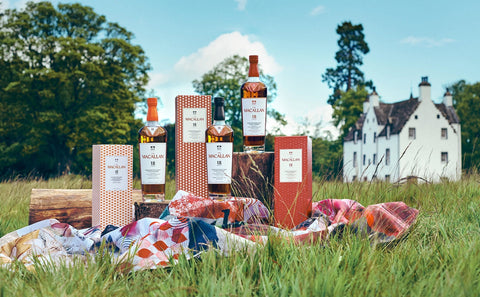Macallan 18 Jahre Single Malt Whisky Flaschen und Geschenkverpackungen auf einer Wiese vor einem weißen Landhaus